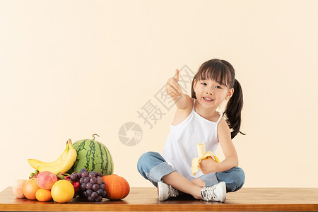 踩着凳子的女孩小女孩开心吃着香蕉背景