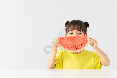 夏天小孩吃西瓜可爱小女孩在桌子上吃西瓜背景