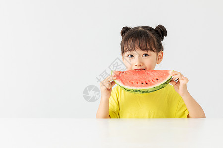 小朋友吃西瓜可爱小女孩在桌子上吃西瓜背景