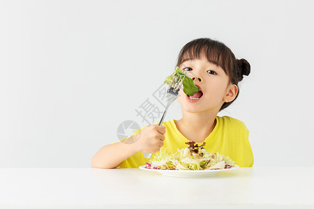 吃东西的女孩小女孩开心的吃着蔬菜沙拉背景