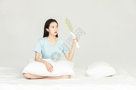 女性坐在床上用电蚊拍图片