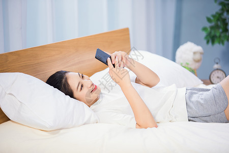 躺在床上的女孩女性躺在床上玩手机背景