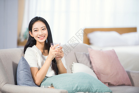 沙发上的女人女性坐在沙发上喝水背景