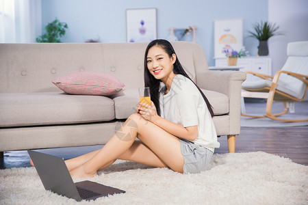 美女喝橙汁女性客厅使用电脑背景