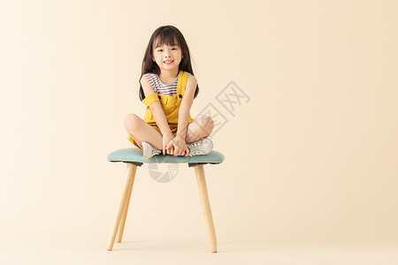 小女孩盘腿坐在椅子上图片