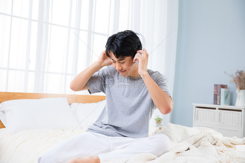 男性卧室戴耳机听音乐图片