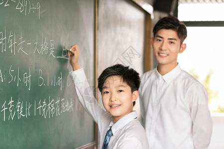 老师和学生微笑着在黑板上做题高清图片
