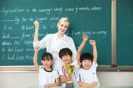 中国人与外国人老师与儿童在教室与奖杯合影背景