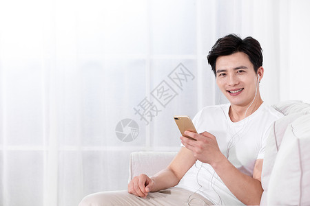 男性坐在沙发上玩手机图片