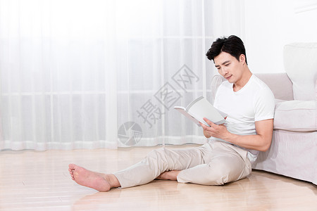 男性坐在地上靠着沙发休息图片