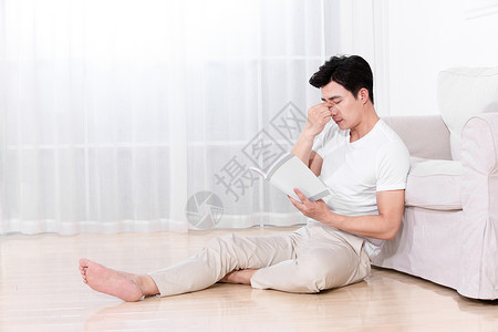 男性坐在地上靠着沙发休息高清图片