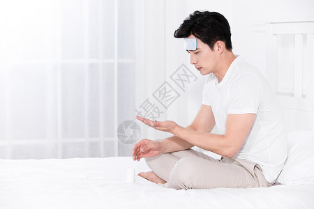 男子发烧坐在床上喝水吃药图片