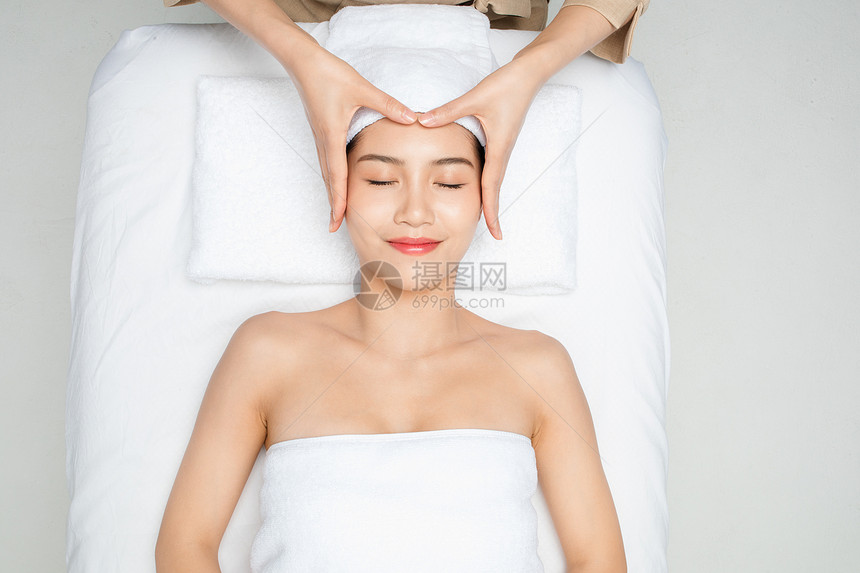 躺在床上做面部按摩的女性图片