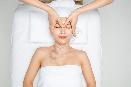 美容spa肌肤护理护肤躺在床上做面部按摩的女性背景