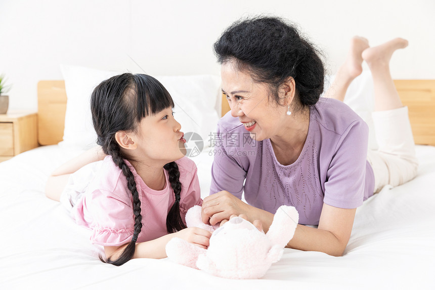 小女孩与奶奶在床上玩娃娃图片
