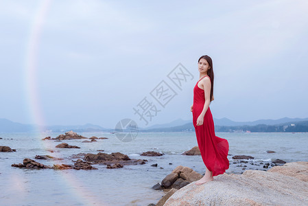深圳较场尾海边礁石上的红衣少女背景图片
