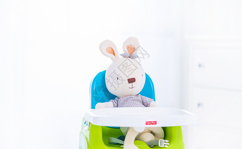 小灰兔去卡通可爱的玩具兔坐在婴儿椅上背景