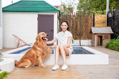 年轻美女主人与宠物金毛犬嬉戏图片