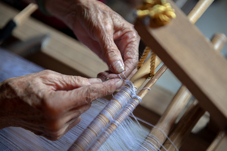 正在旋转正在织布的老奶奶的双手背景