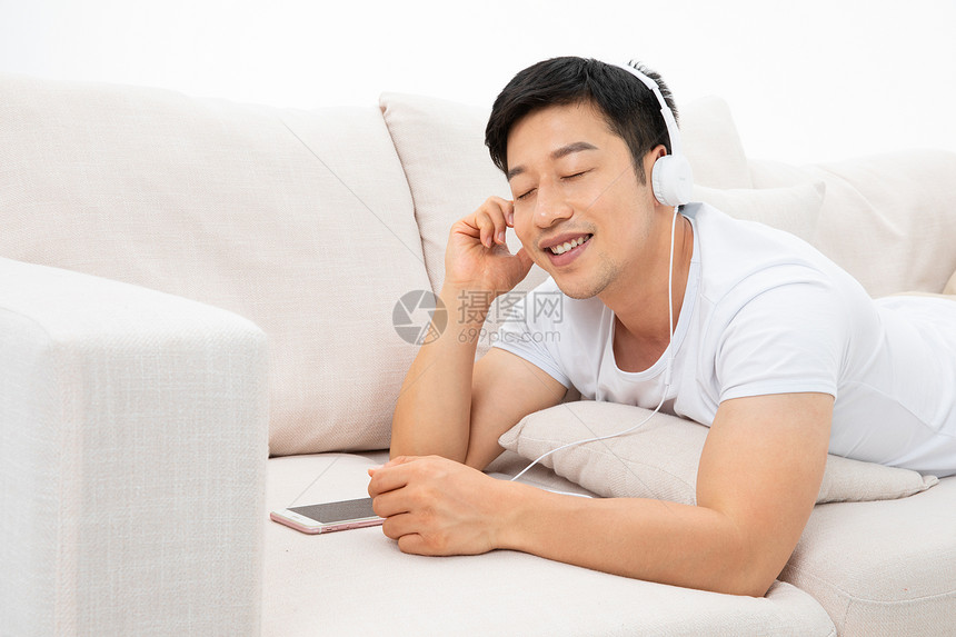 青年男性居家玩手机听音乐图片