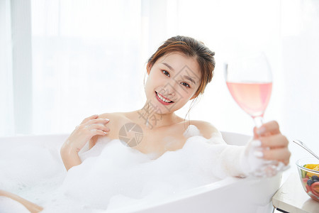 美女躺在浴缸洗泡泡浴喝鸡尾酒图片