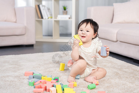 6个月女婴在地毯上玩积木背景