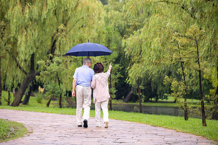 老年夫妇雨中散步背影高清图片