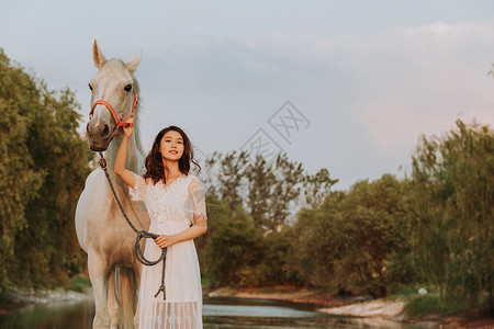 亚洲矮马年轻女性与白马背景