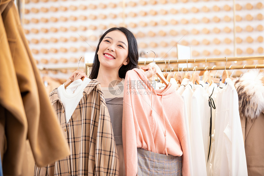 年轻美女逛街购物挑选衣服图片