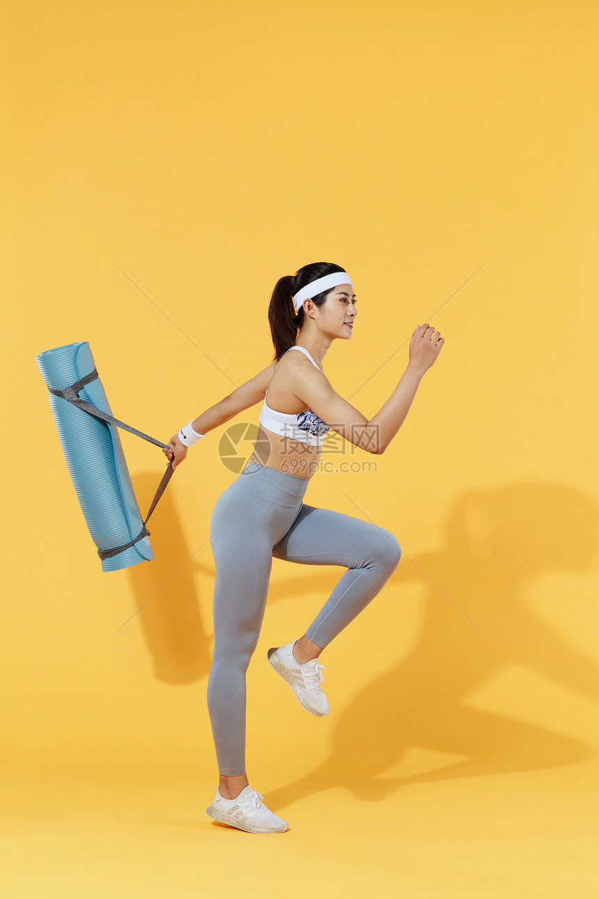 女性背着瑜伽垫图片