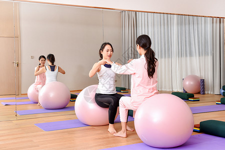 身材恢复产妇和教练一起练习瑜伽球背景