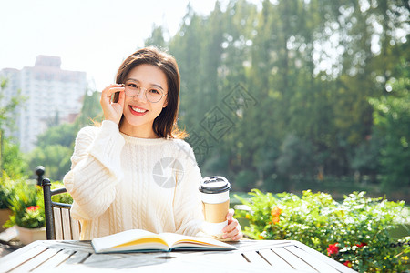 室外咖啡桌喝咖啡的女大学生背景