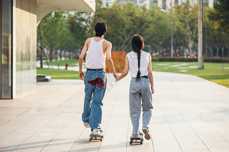 情侣户外玩滑板背影高清图片