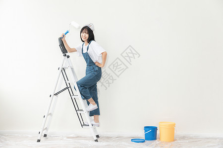 青年女性爬梯子刷墙形象图片