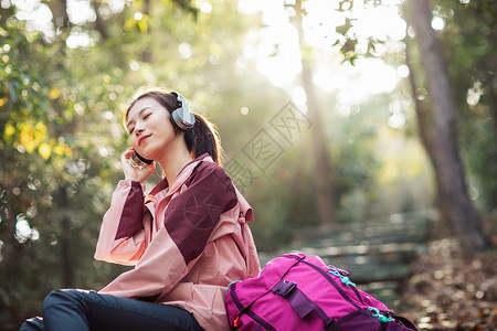 背包的女生女生坐在山间小路上听音乐背景