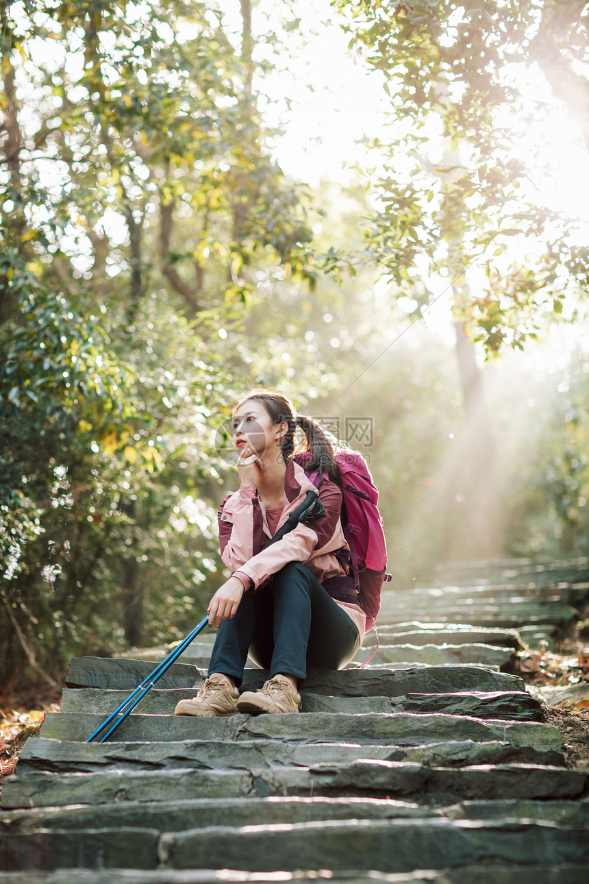 女生坐在山间小路上休息图片