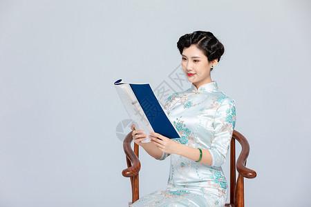 旗袍美女坐椅子上看书背景图片