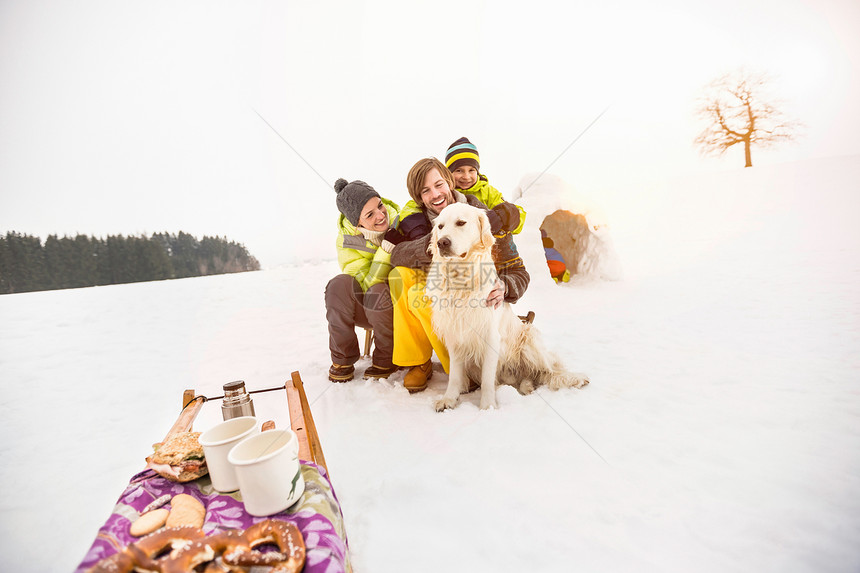 父母和儿子在雪地里抱着狗图片