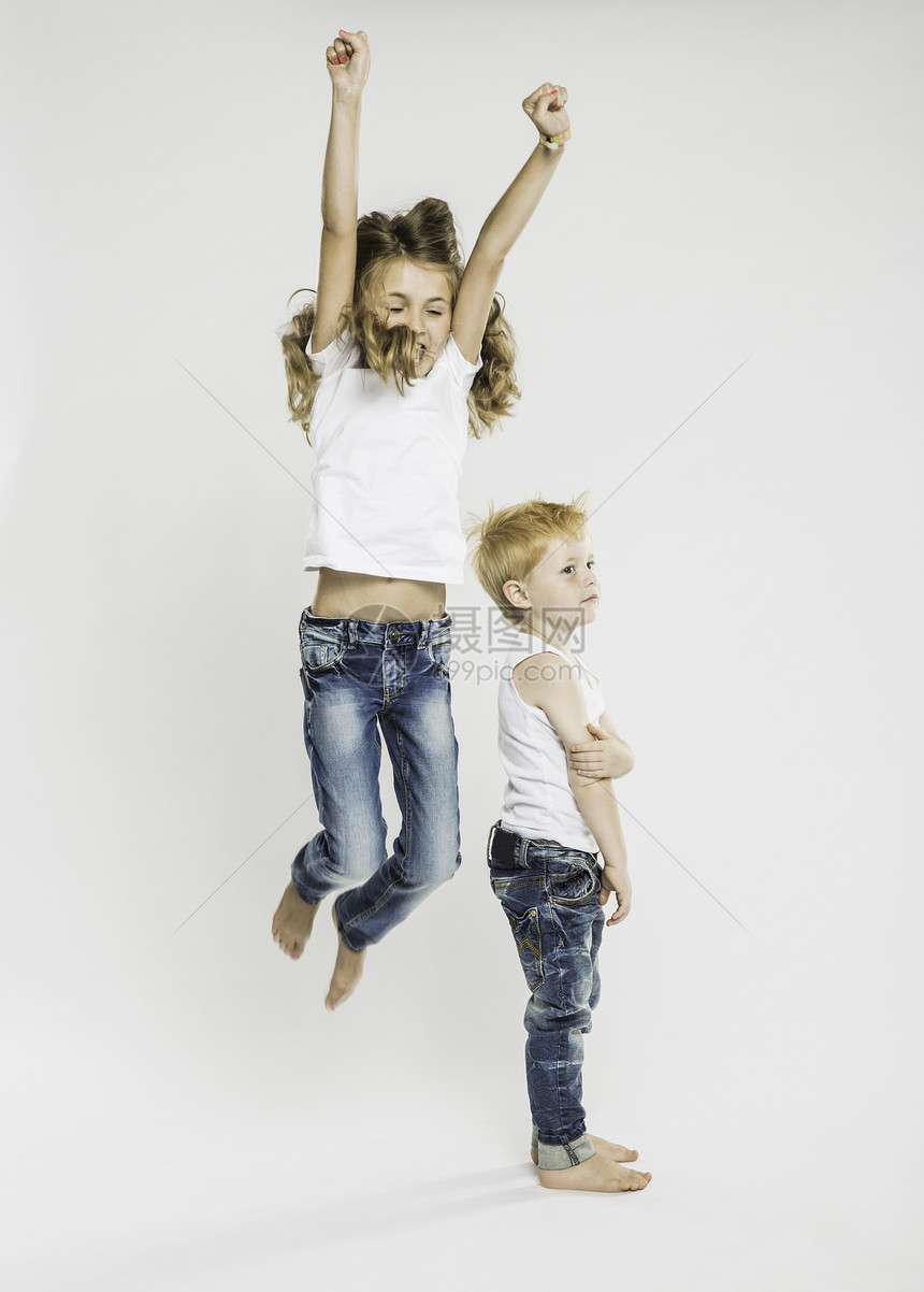 男孩站着和妹妹在空中跳跃的摄影棚肖像图片
