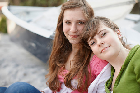 两个女孩一起坐在海滩上图片
