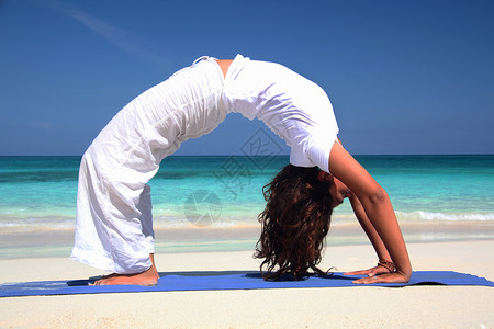 拱背在海滩天堂岛拿骚巴哈马练习瑜伽的年轻女子背景