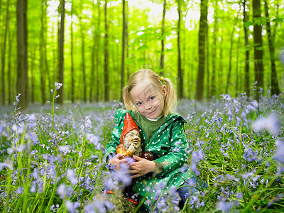 在树林里有个女孩在花园和侏儒拥抱背景图片