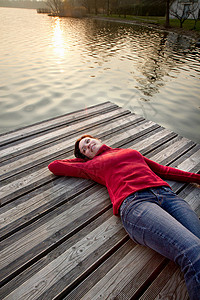 女人躺在湖上的码头上图片