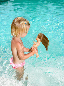 在游泳池里玩洋娃娃的小女孩图片
