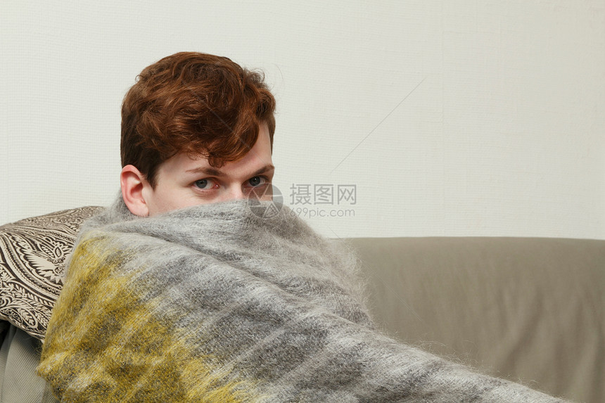 在沙发上裹着毯子的男人图片