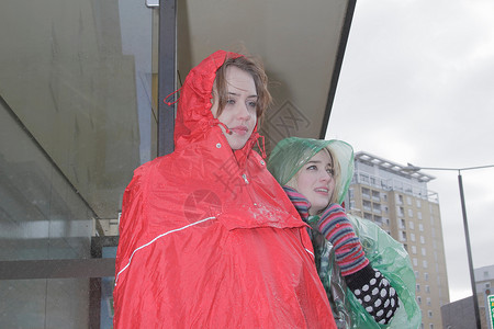 两个穿雨衣的女性在等公车背景图片