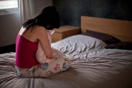 家里的心烦意乱的女人把枕头抱在床上背景