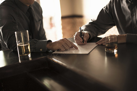 签名坐合作伙伴在酒吧签署商业合同背景