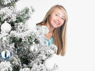 站在圣诞树后微笑的女孩图片