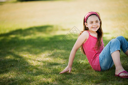 坐在草地上笑的小女孩图片